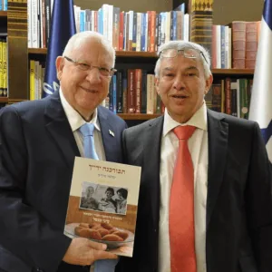 ראובן ריבלין וגבר נוסף עם ספר הבישול מול דגלי ישראל