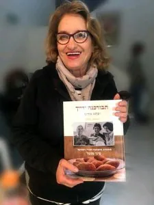 סיגי מנטל מחייכת ומחזיקה את ספרה תבורכנה ידייך באירוע