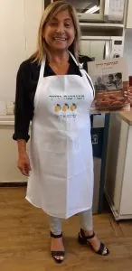 סינר לבן רקום בלוגו לימונים תלוי במטבח